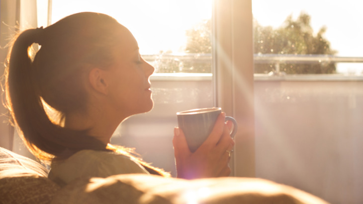 Žena uživa u kavi u sobi grijanoj na toplinske mreže i daljinsko grijanje.