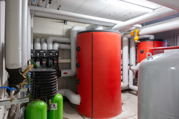 Bild eines Hoval Warmwasser-/Pufferspeichers in rot eingebaut in einen Kellerraum. 